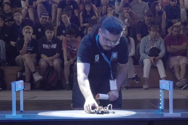 Un competidor ubica su robot en la partida de la pista, frente al público, en el All Chile Robot Contest